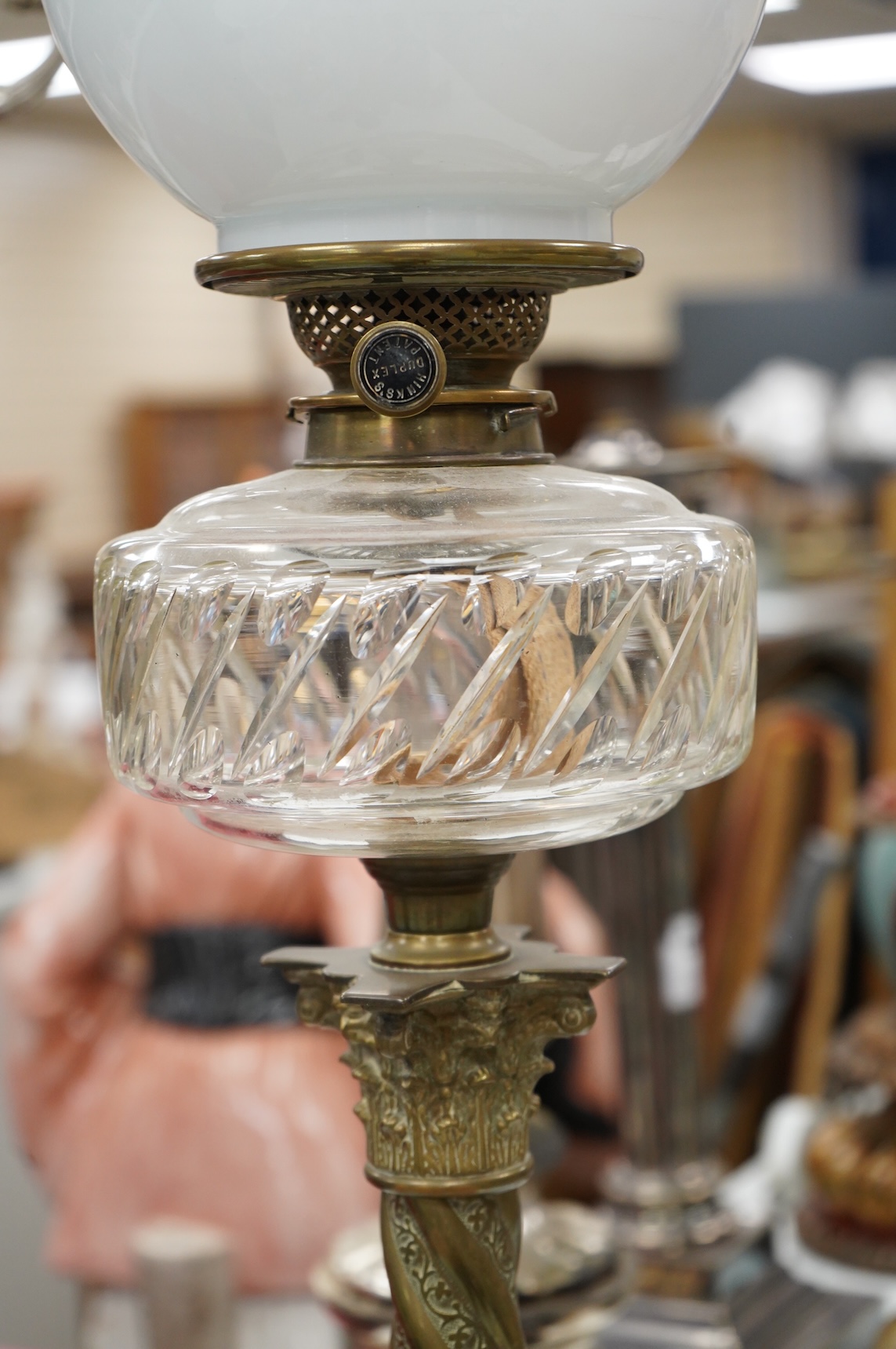 A brass corinthian column oil lamp with glass reservoir and opaque glass shade, 78cm high
